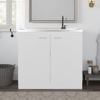 White laundry cabinet with sink in a room with a window and small table.